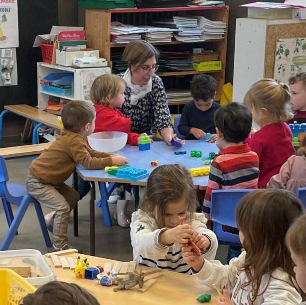 Sylvie P. enseignante à l'école de l'annonciation annecy entourée de ses élèves
