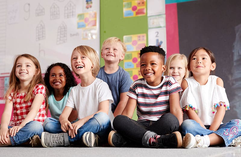 enfants de toute religion souriant assis sur le sol
